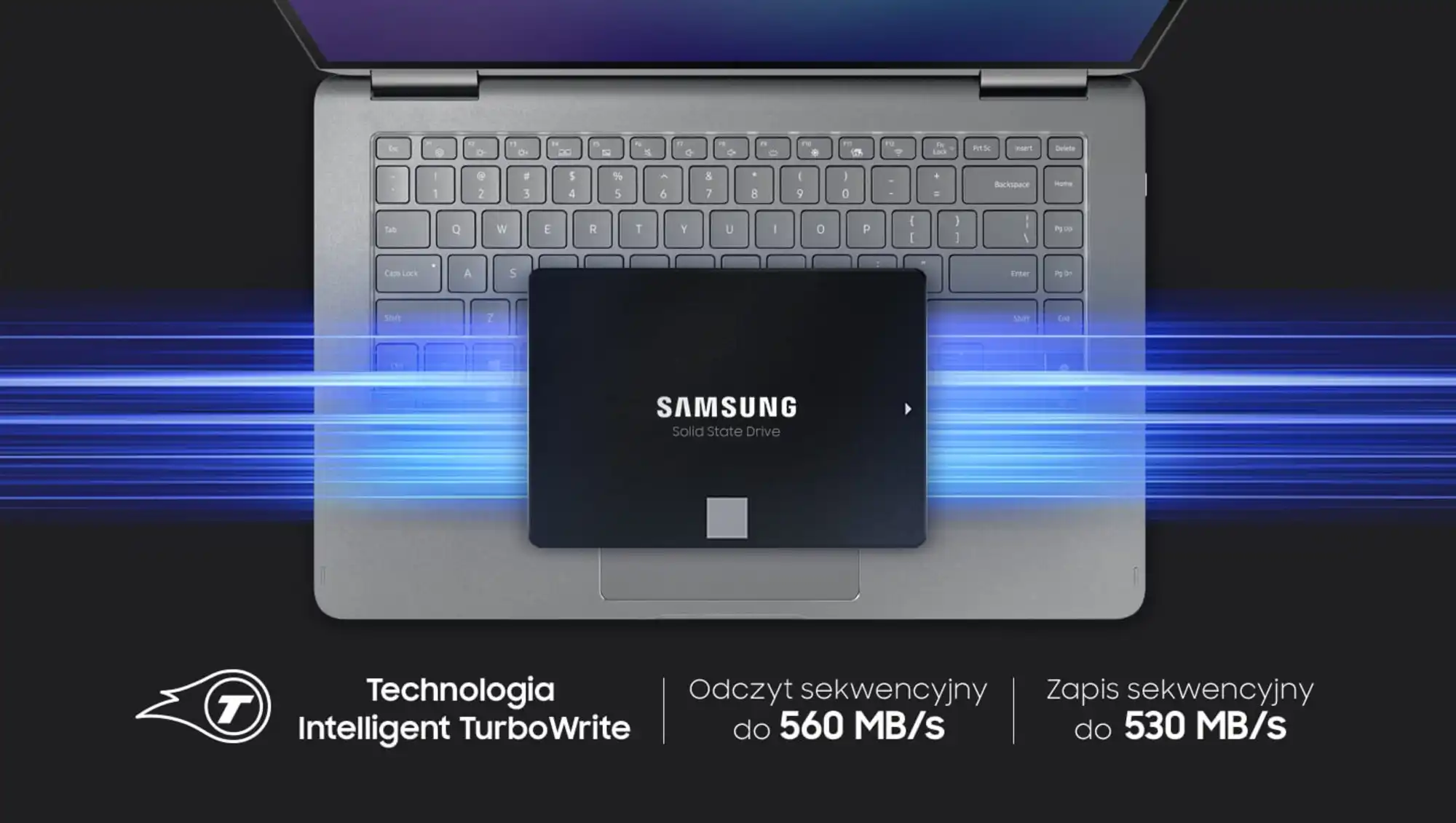 Dysk Samsung umieszczony na środku, na tle klawiatury srebrnego laptopa, w poziomie pod dyskiem przebiegają niebieskie kreski. W dolnej części zdjęcia znajdują się napisy - Technologia Intelligent TurboWrite; Odczyt sekwencyjny do 560 MB/s; Zapis sekwencyjny do 530 MB/s